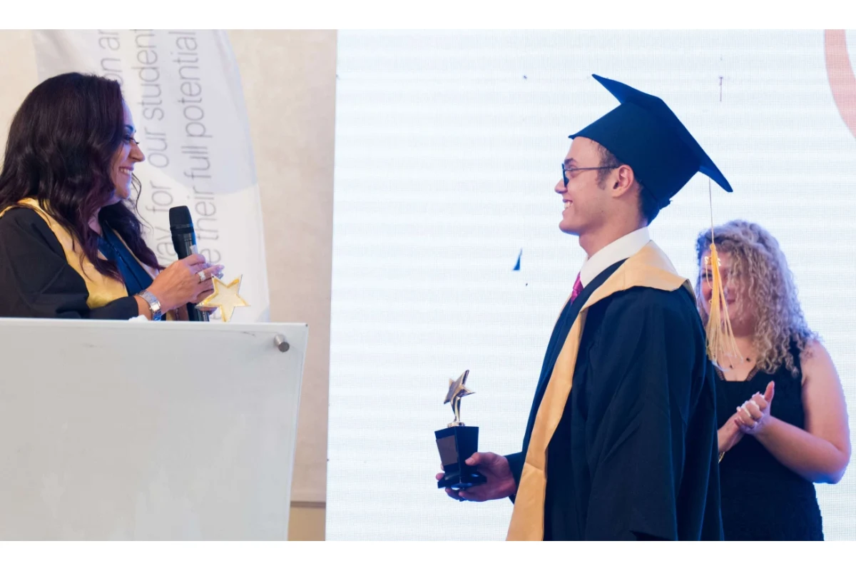 Ali receiving an award on stage in graduation attire